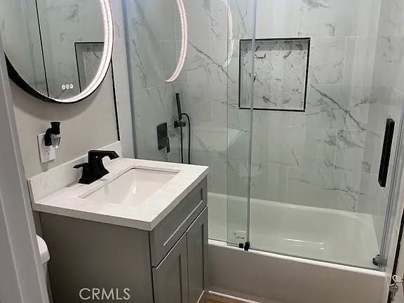 Marble-look tile, gray vanity, and LED mirror