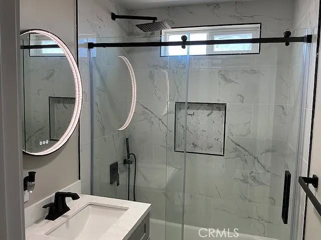 Marble-look tile surround, recessed niche, and frameless glass shower door
