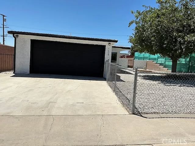 Garage with a new door, fresh stucco, and updated hardscape